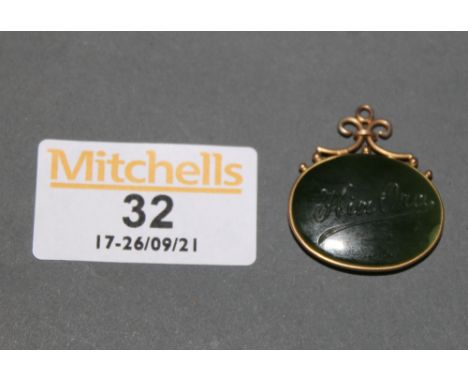 A gilt metal mounted jade oval pendant engraved to front with native figure and to reverse worded Kia Ora 