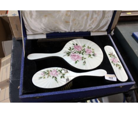 A cased enamelled 3 piece dressing table set and a silver mounted comb