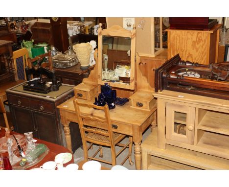 An Edwardian stripped pine dressing table and a cane seat ladder back bedroom chair 