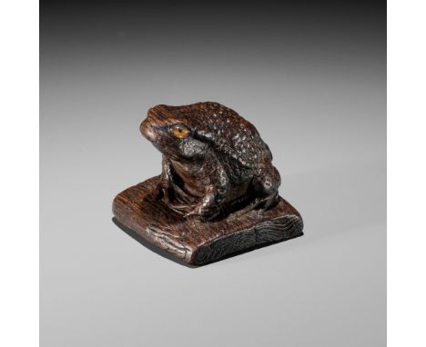 AN UNUSUAL PAULOWNIA (KIRI) WOOD NETSUKE OF A TOAD ON ROOF TILEUnsignedJapan, early 19th century, Edo period (1615-1868)The f