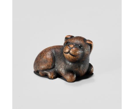 A TANBA SCHOOL WOOD NETSUKE OF A RECLINING PUPPYUnsignedJapan, Tanba Province, 19th century, Edo period (1615-1868)The reclin