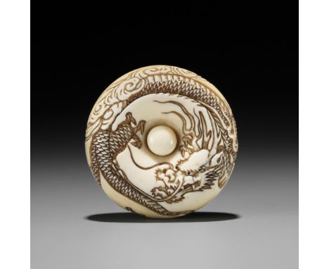 A LARGE IVORY MANJU NETSUKE OF A DRAGON ABOVE WAVESUnsignedJapan, mid-19th century, Edo period (1615-1868)The thick manju net