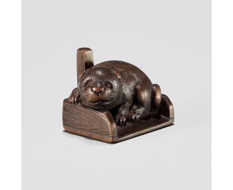 KOKEI: A WOOD NETSUKE OF A PUPPY INSIDE A DUSTPANBy Kokei, signed Kokei 虎溪Japan, Kuwana, Ise Province, 19th century, Edo peri