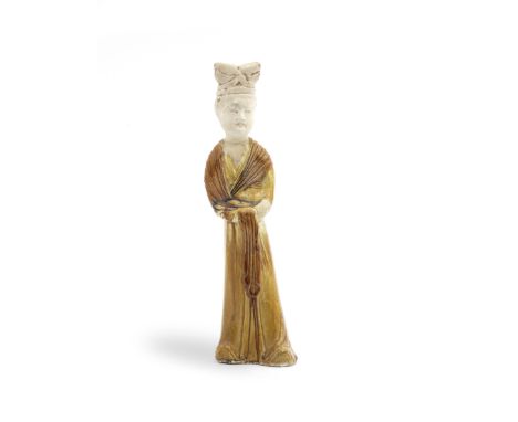 AN AMBER-GLAZED POTTERY FIGURE OF A LADYTang DynastyGracefully modelled standing with the hands held together at her waist un