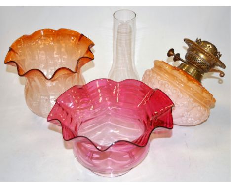 A collection of oil lamp parts and accessories, to include reproduction cranberry tinted frilled glass shade, etched orange t