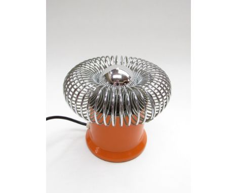 A table lamp with cylindrical orange base and chromed metal spring diffuser