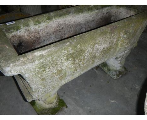 A large stone trough, decorated with lion heads, with 2 watching bases