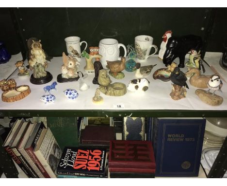 A shelf of bird and animal figures, including owls and owl mugs