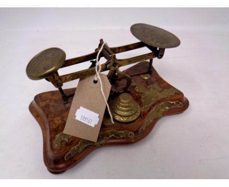 A set of ornate 19th century brass postal scales with graduated weights, mounted on a walnut base 