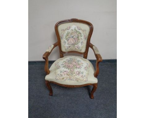 A carved beech framed French salon armchair upholstered in a tapestry fabric  