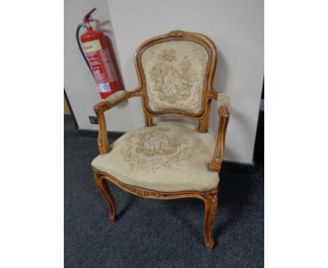 A carved beechwood French salon armchair upholstered in a tapestry fabric  