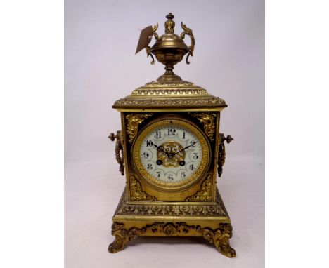 An ornate nineteenth century brass mantel clock with brass and enamel dial surmounted by a twin handled urn 