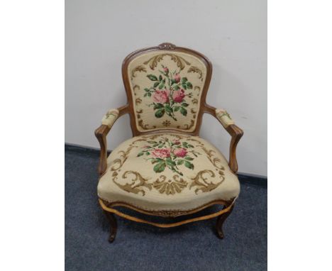 A carved beech framed French salon armchair upholstered in a tapestry fabric  