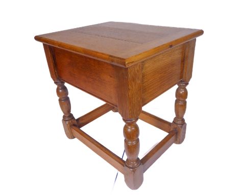 An oak joint-style stool with cleated hinged top and turned legs united by moulded stretchers