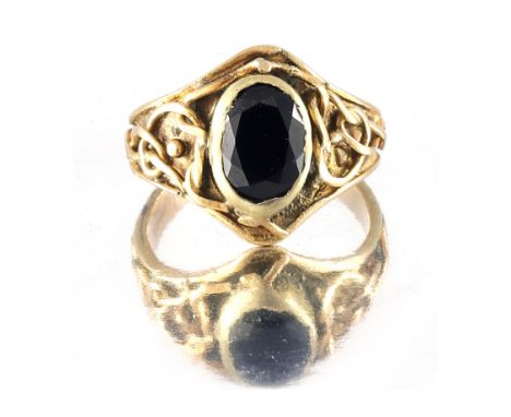 Mary Thew (attributed), an Arts and Crafts Glasgow School gold garnet ring, in the Iona style, the oval-shape gemstone flanke