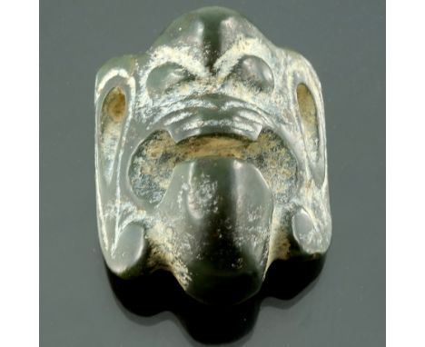 An oriental carved dark green jade netsuke, 20th Century, carved as a grotesque face mask with large ears, height 4.5cm