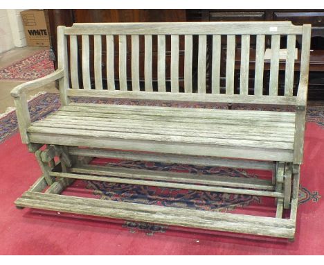 A teak garden rocking bench with foot rest, 150cm long.