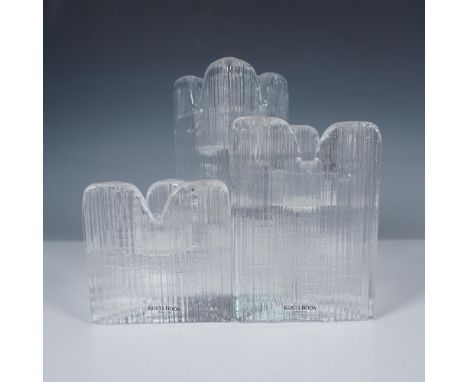 Illuminate your space with this exquisite set of three Kosta Boda candle holders, designed by renowned artist Anna Ehrner. Th