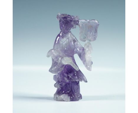 Hand-carved amethyst figurine depicting a robed female figure holding a fan. The translucent lavender gemstone reveals natura