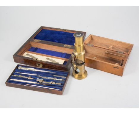 A lacquered brass student field microscope, single eye-piece, hinged lens, 16cm high in mahogany case, a set of drawing instr