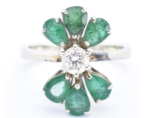 An 18t gold emerald and diamond cluster ring. The ring set with a central round brilliant cut diamond flanked by 6 pear cut e