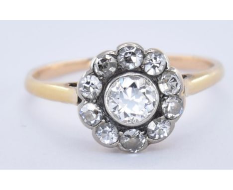 An 18ct gold and diamond cluster ring. The ring set with a central old cut diamond surrounded by 10 old cut diamonds. Tests i