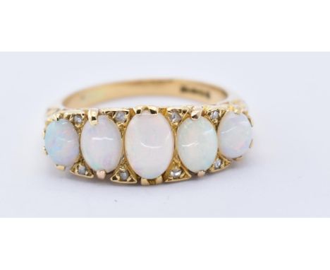 An 18ct gold opal five stone ring. Hallmarked London, 1969, the ring with 5 cabochon opals to a gypsy setting on plain taperi