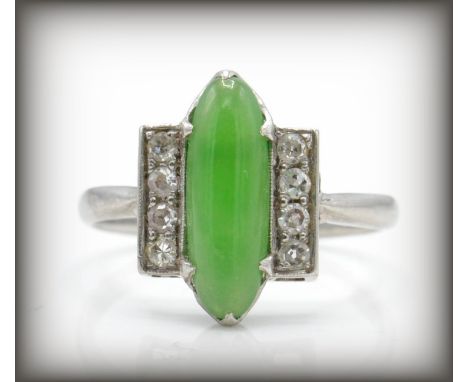 An Art Deco platinum, diamond and Chinese Jade ring. The ring set with a green cabochon possible nephrite. Flanked by two row