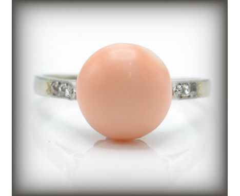 An early 20th century&nbsp; French 18ct gold coral and diamond ring. The ring having a central angel skin cabochon flanked by