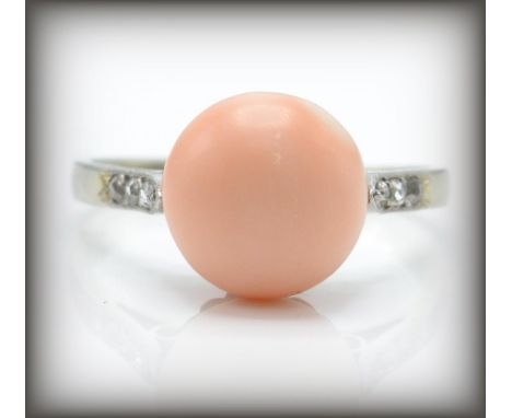 An early 20th century&nbsp; French 18ct gold coral and diamond ring. The ring having a central angel skin cabochon flanked by