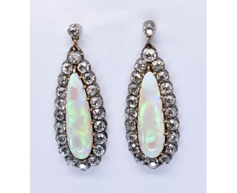 A pair of antique opal and diamond pendant earrings. The earrings set with central pear cut opal cabochon framed by colette s