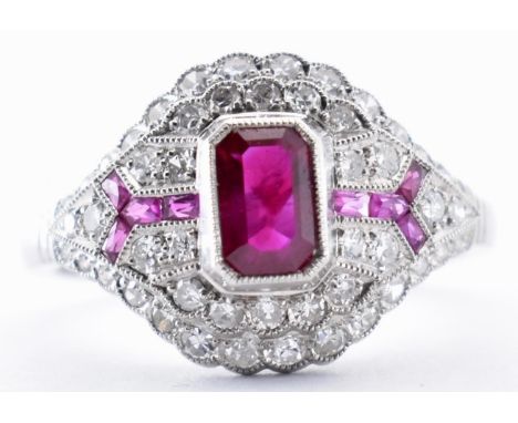 An 18ct white gold, ruby and diamond Art Deco style dome cluster ring. The ring set with a&nbsp; central emerald cut ruby fla