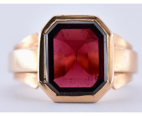 A French 18ct gold Art Deco garnet signet ring. The ring set with an emerald cut garnet to stylised shoulders and tapering sh