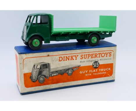 Dinky - A boxed Guy Flat Truck with tailboard in dark green with light green wheels and back # 513. The model appears in Very