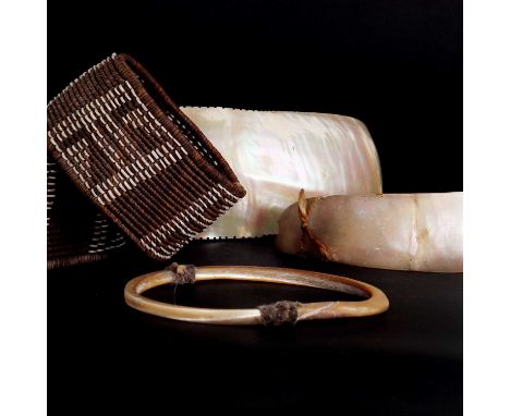 Three shell artefacts,19th century, Solomon Islands,a bangle,9.5cm diameter,an ornament with a serrated edge,17cm long, anda 