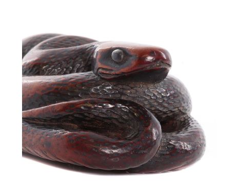 A Japanese boxwood netsuke,Edo period, 18th century, in the form of a coiled snake with inset white metal and enamel eyes,5.5