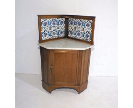An Edwardian mahogany corner washstand, with marble top and William Morris style tiled back.