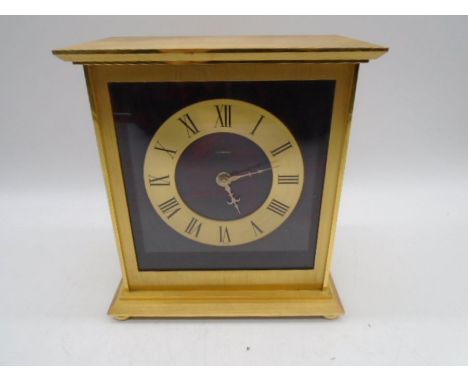 A contemporary brass mantle clock by Looping, with faux tortoiseshell background, quartz movement