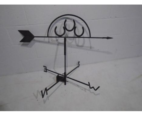 A vintage wrought iron weather vane with three horseshoes