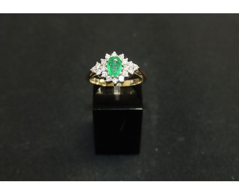 A 9 carat hallmarked gold dress ring set oval emerald surrounded by 18 small diamonds, size R/S, 3.8 gm