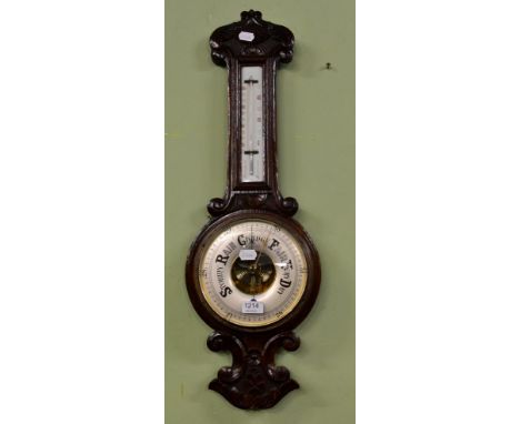 A carved oak wheel barometer and thermometer 