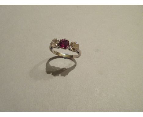 A ruby and diamond three stone ring, the round cut ruby claw set between two round brilliant cut diamonds to a plain tapered 