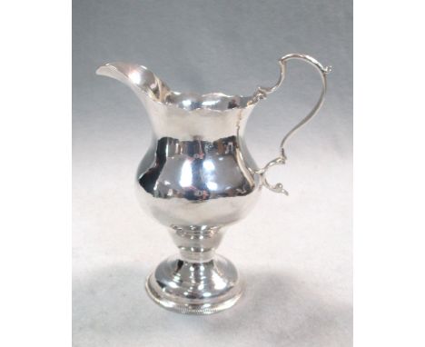 A George III silver cream jug, by Hester Bateman, London 1775, pyriform below a cut edge, flying scroll handle, raised on a c