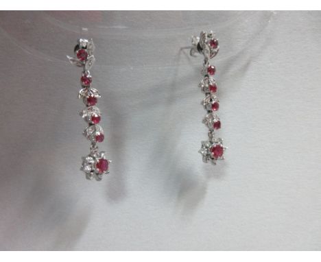 A pair of ruby and diamond earpendants, each post headed by a round cut ruby framed by diamond set pointed leaves and suspend