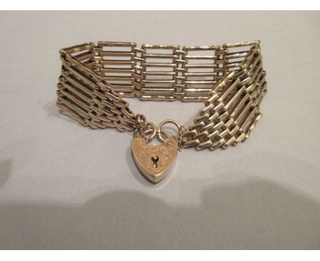 A 9ct gold gatelink bracelet, composed of alternating longer 'gate' links and shorter joining links to tapered ends, heart lo