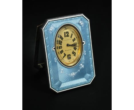 A Swiss silver and enamelled case strut bedside clock, pale blue ground with engine turning and white floral motifs, oval gil