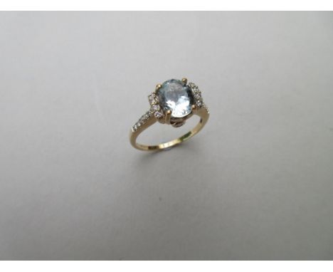 An aquamarine and diamond ring, the oval cut aquamarine four claw set between lines of round brilliant cut diamonds, the shou