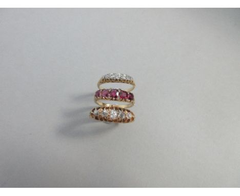 Two diamond five stone rings and a similar ruby ring with diamond highlights, the first with graduated old round to cushion c