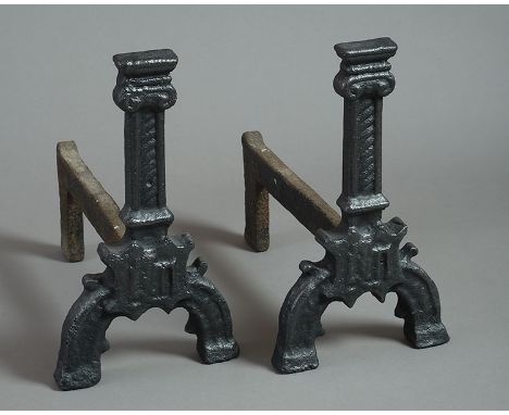 A pair of 16th century Gothic Andirons, the capped pillars with hatched decoration, a shield initialled IHS, on gothic arched