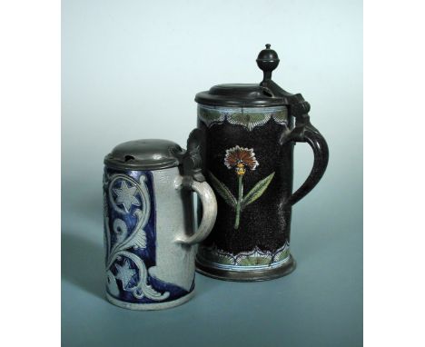 A German faience and pewter mounted lidded tankard, the body decorated with a shaped cartouche containing floral sprays, rese